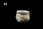Handmade glass cup with a rounded shape, shimmering gold and blue textured swirls, and a pale blue rim against a black background