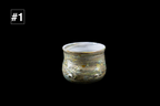 Handmade glass drinking cup with shimmering gold and silver layers, a rounded shape, and a pale rim against a black background
