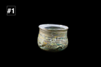 Handmade glass cup with a softly flared rim and shimmering green gold and blue swirls creating a richly textured surface against a black background