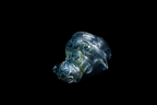 Handmade blue and silver glass cup with sculpted flowing ocean waves and a rounded organic form displayed against a black background