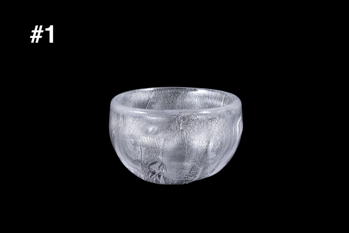 Handmade silver toned glass guinomi cup with a rounded bowl shape and shimmering textured surface displayed against a black background