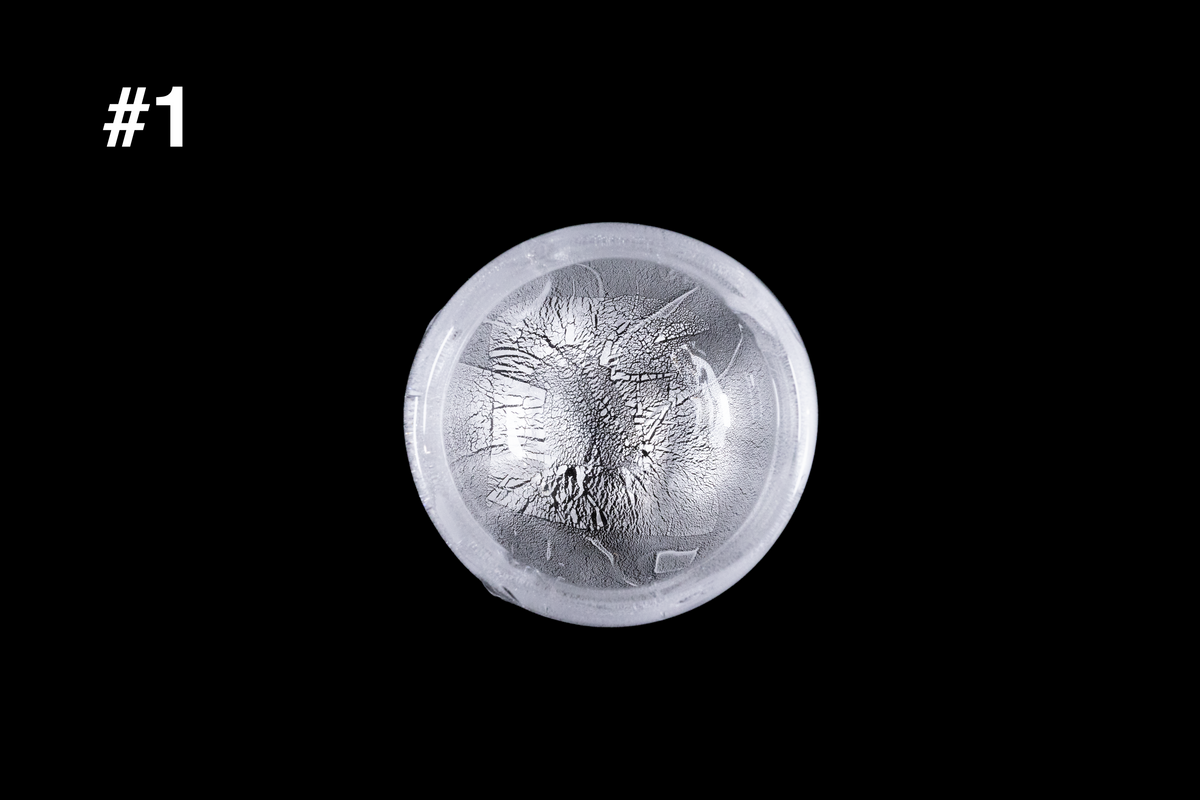 Translucent silver glass sake cup with a textured snowflake like pattern and softly rounded rim displayed against a black background