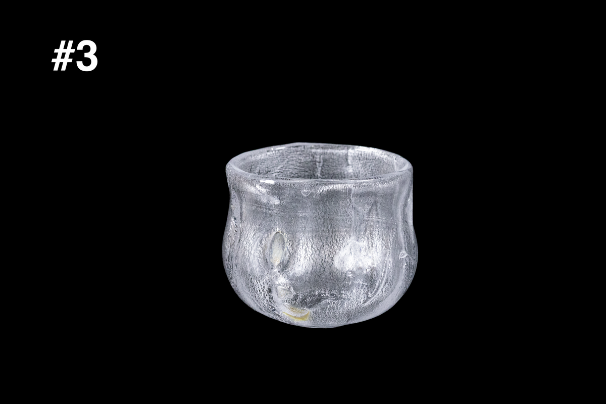 Handmade clear silver toned guinomi cup with a rippled textured surface and softly rounded rim against a black background