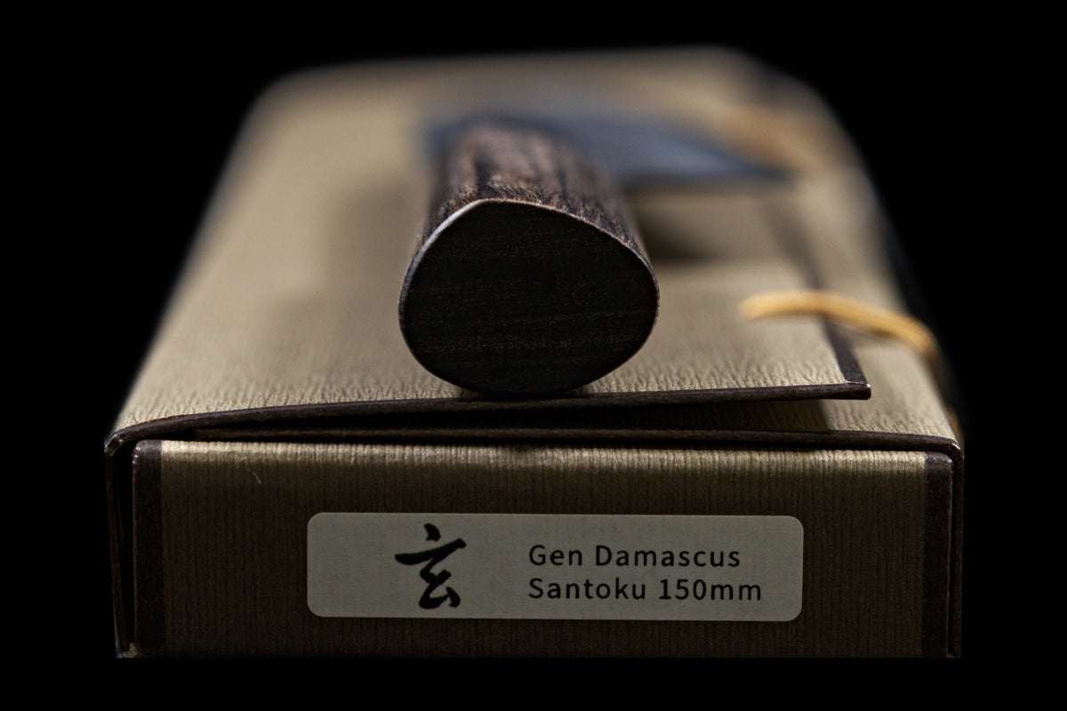 Gen 150mm Kurouchi Santoku, end of the handle viewed head-on, showing the handle shape, resting on its box
