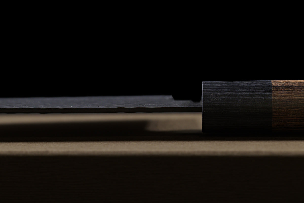 Gen 150mm Kurouchi Santoku, side view of the spine near the handle, showing spine thickness and ferrule