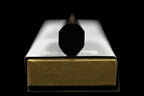 Octagonal ebony handle end of the Gesshin Uraku 210mm White #1 Mizu Honyaki Wa-Gyuto resting on its box