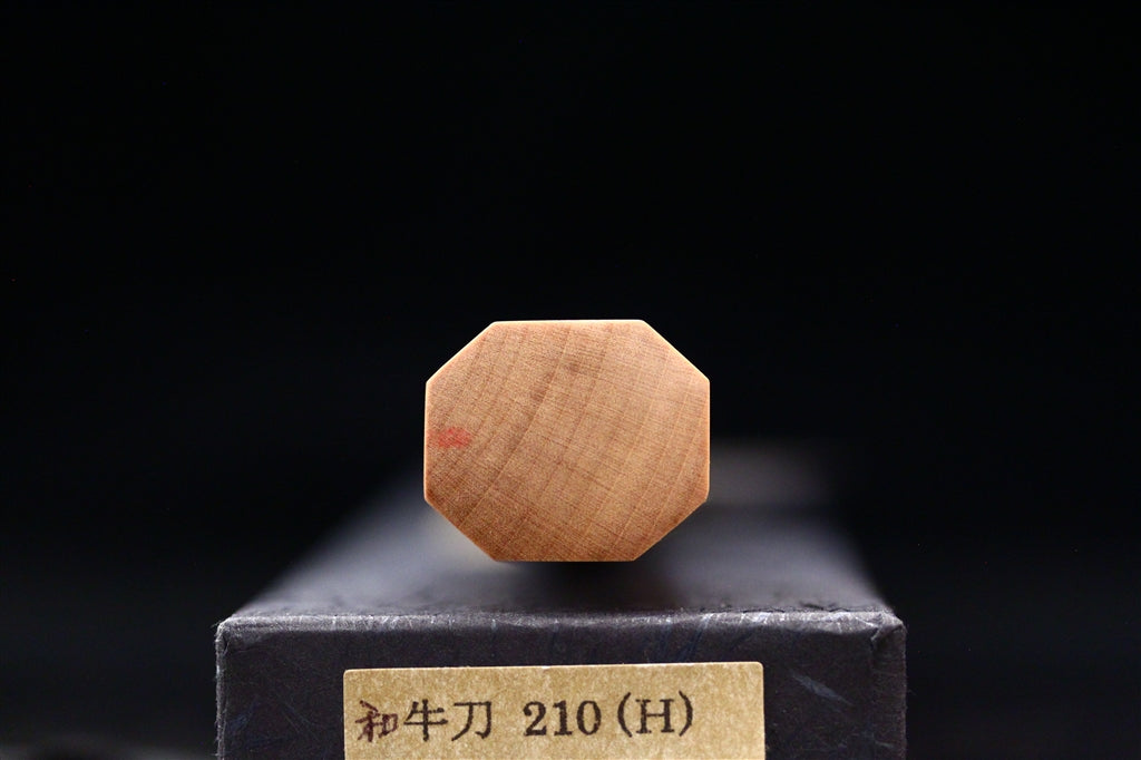 End view of the octagonal ho wood handle from an Ashi Hamono Gesshin Ginga 210mm carbon wa gyuto resting on its labeled black presentation box