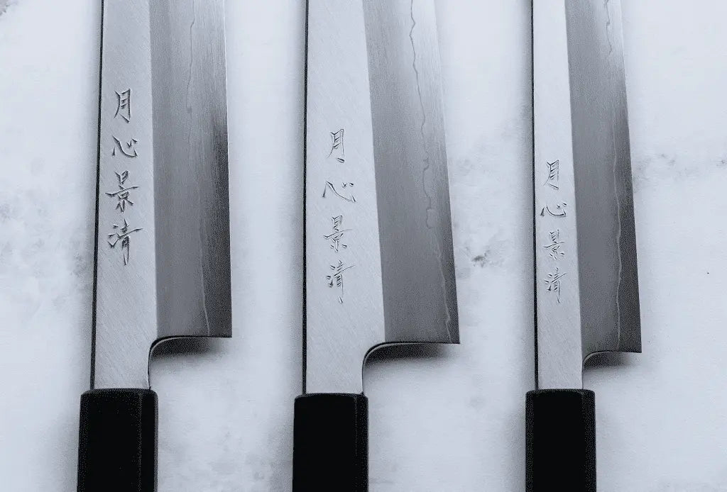 Set of four Japanese knives with engraved names on a light background